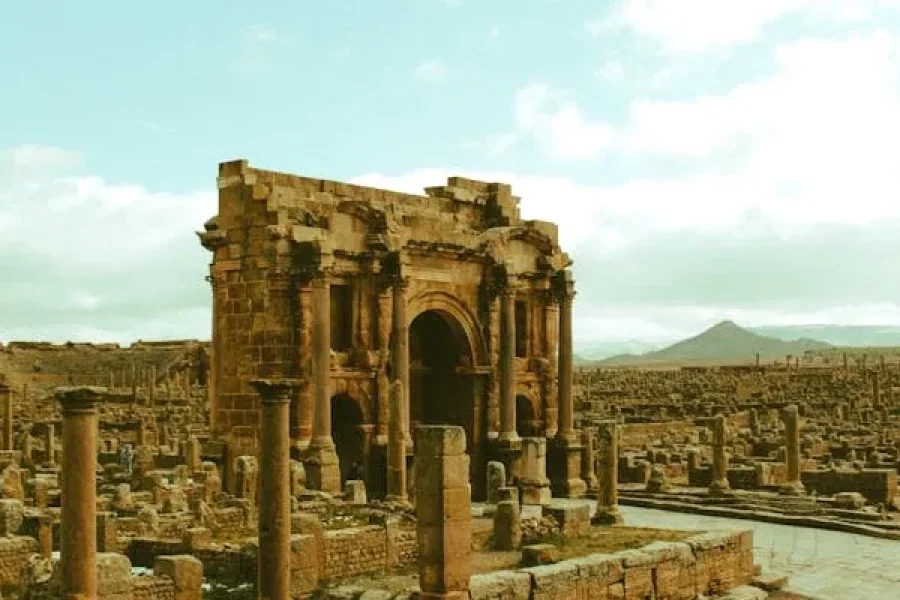 Ancient stone ruins with an arched doorway and rows of columns under a blue sky